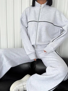 Detail eines hellgrauen Tracksuits mit schwarzen Seitenstreifen und Reißverschluss-Oberteil