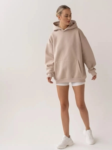 Detail of oversized beige hoodie featuring a kangaroo pocket and ribbed cuffs for women