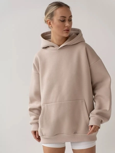 Close-up of oversized apricot hoodie showing kangaroo pocket and soft fabric texture