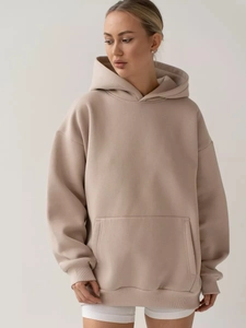 Close-up of oversized light beige hoodie with ribbed cuffs and large kangaroo pocket
