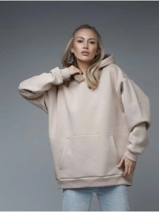 Detail of beige oversized hoodie featuring kangaroo pocket and ribbed cuffs in soft cotton