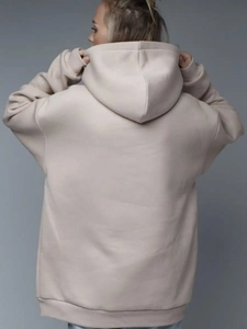 Back view of women's oversized beige hoodie featuring ribbed cuffs and a large hood