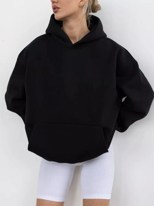 Detail of loose fit black hoodie with kangaroo pocket and dropped shoulder design
