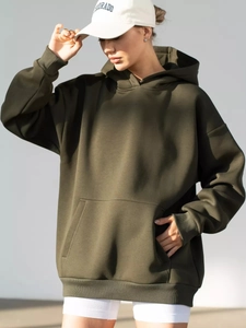 Detail of dark olive oversized hoodie featuring a front kangaroo pocket and ribbed cuffs