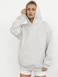 Close-up of oversized light grey hoodie showing kangaroo pocket and ribbed sleeve cuffs