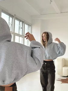 Detail eines grauen kurzen Kapuzenpullis mit Reißverschluss und elastischen Bündchen