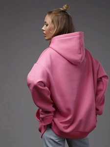 Rear view of an oversized pink hoodie showing the loose fit and ribbed cuff details