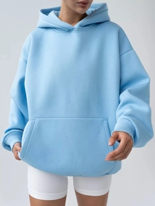 Detail of light blue oversized hoodie featuring drop shoulders and front kangaroo pocket