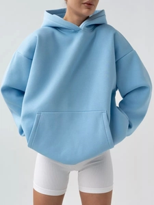 Detail of light blue oversized hoodie featuring a kangaroo pocket and drop shoulders