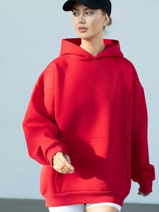 Detailed texture of an oversized red hoodie with kangaroo pocket and ribbed cuffs