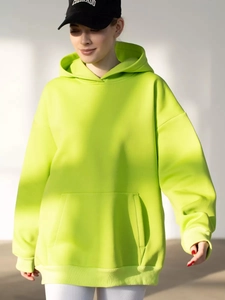Detail of neon green oversized hoodie with kangaroo pocket and ribbed cuffs in soft light