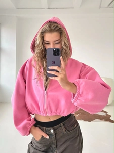 Detail eines rosa bauchfreien Kapuzenpullovers mit Reißverschluss und elastischen Bündchen