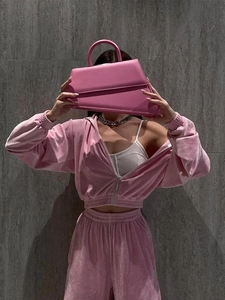 Close-up of pink velvet tracksuit texture with silver chain and stylish trapezoid handbag