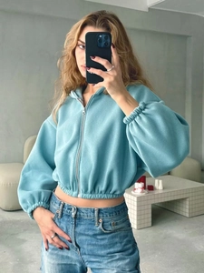 Detail eines hellblauen Crop-Zip-Hoodies mit Jeans-Outfit in einer Spiegel-Selfie-Ansicht