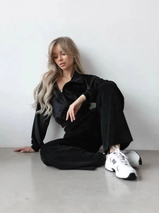 Detail of soft black velvet texture on women's zip-up tracksuit with wide-leg pants