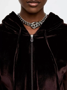 Close-up of dark brown velvet hoodie with metallic zipper and chunky silver chain necklace