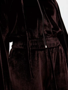 Close-up of the plush velvet texture and elastic waistband of the dark brown tracksuit
