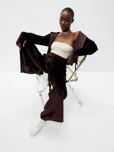 Detail of dark brown velvet tracksuit featuring zip-up hoodie and wide-leg drawstring pants