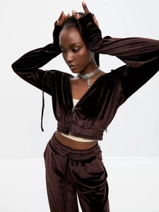 Detail of dark brown velvet tracksuit featuring a cropped zip hoodie and matching pants