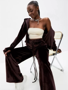 Detail of soft velvet zip-up hoodie and high-waisted wide-leg joggers in deep brown fabric