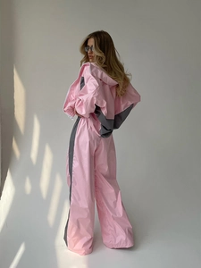 Dettaglio della tuta oversize rosa e grigia a contrasto con pantaloni a gamba larga