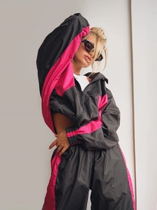 Dettaglio della tuta sportiva con cappuccio e zip nei colori a contrasto nero e rosa