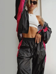 Dettaglio dei pantaloni a vita alta e giacca corta in nero e rosa acceso sportivo