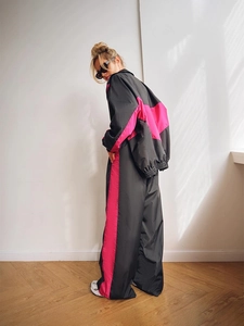 Dettaglio di una tuta bicolore con inserti rosa e neri sui pantaloni a gamba larga