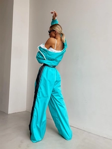 Dettaglio completo del set sportivo turchese con strisce laterali nere e pantaloni larghi