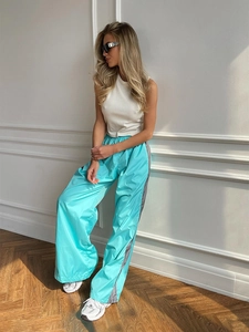 Dettaglio del crop top bianco a coste abbinato a pantaloni larghi blu acceso con strisce laterali