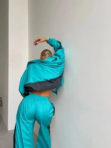 Vista posteriore di una tuta sportiva oversize da donna in blu e grigio con strisce