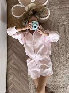 Detail of light pink zip-up hoodie and matching shorts set on wooden flooring
