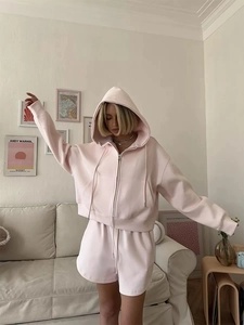 Close-up of pink hooded sweatshirt and drawstring shorts set in a cozy home setting