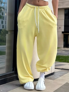 Dettaglio dei pantaloni sportivi larghi giallo chiaro con coulisse bianca regolabile