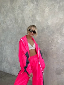Dettaglio della giacca con zip rosa neon e pantaloni sportivi con inserti a contrasto