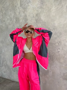 Dettaglio della tuta antivento con blocchi di colore rosa neon e grigio scuro e zip