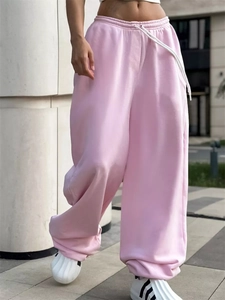 Dettaglio dei pantaloni sportivi rosa a gamba larga con vita alta e coulisse bianca