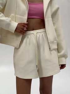 Close-up of cream zip-up hoodie, pink ribbed crop top and drawstring shorts detail