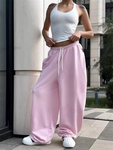 Dettaglio dei pantaloni rosa a gamba larga con vita alta, coulisse e tessuto fluido di qualità