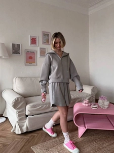 Detail of grey hooded zip-up sweatshirt and loose shorts set in a cozy interior setting