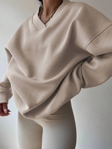 Detail view of beige oversized V-neck sweatshirt and ribbed leggings fabric texture