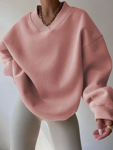 Detail of pink oversized sweatshirt showing ribbed V-neckline and heavy fabric texture