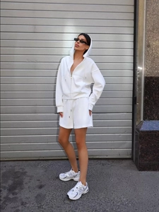 Profile view of model in white hooded sweatshirt and matching drawstring shorts set