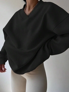 Detail of a black oversized ribbed V-neck sweatshirt featuring premium smooth knit fabric