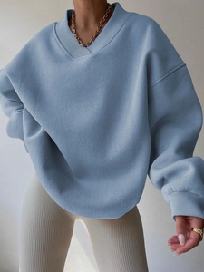 Detail of light blue oversized sweatshirt with V-neck and ribbed cuffs on a model