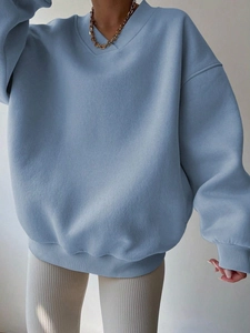 Detail of light blue oversized sweatshirt featuring ribbed V-neckline and soft cotton fabric