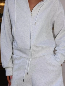 Detail of heather gray hooded sweatshirt with metal zipper and matching casual trousers
