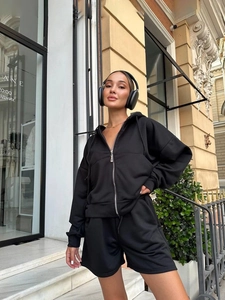 Close-up of black hooded zip-up sweatshirt and wide-leg shorts set in casual urban setting