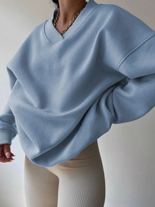 Detail of light blue oversized V-neck sweatshirt featuring ribbed cuffs and a cozy knit fabric