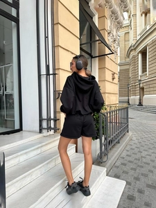 Rear view of black minimalist oversized hoodie and high-waist shorts set in street style
